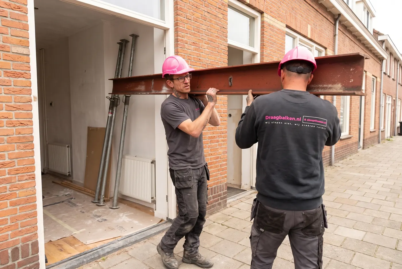 Twee medewerkers van Draagbalken.nl dragen een stalen draagbalk naar binnen