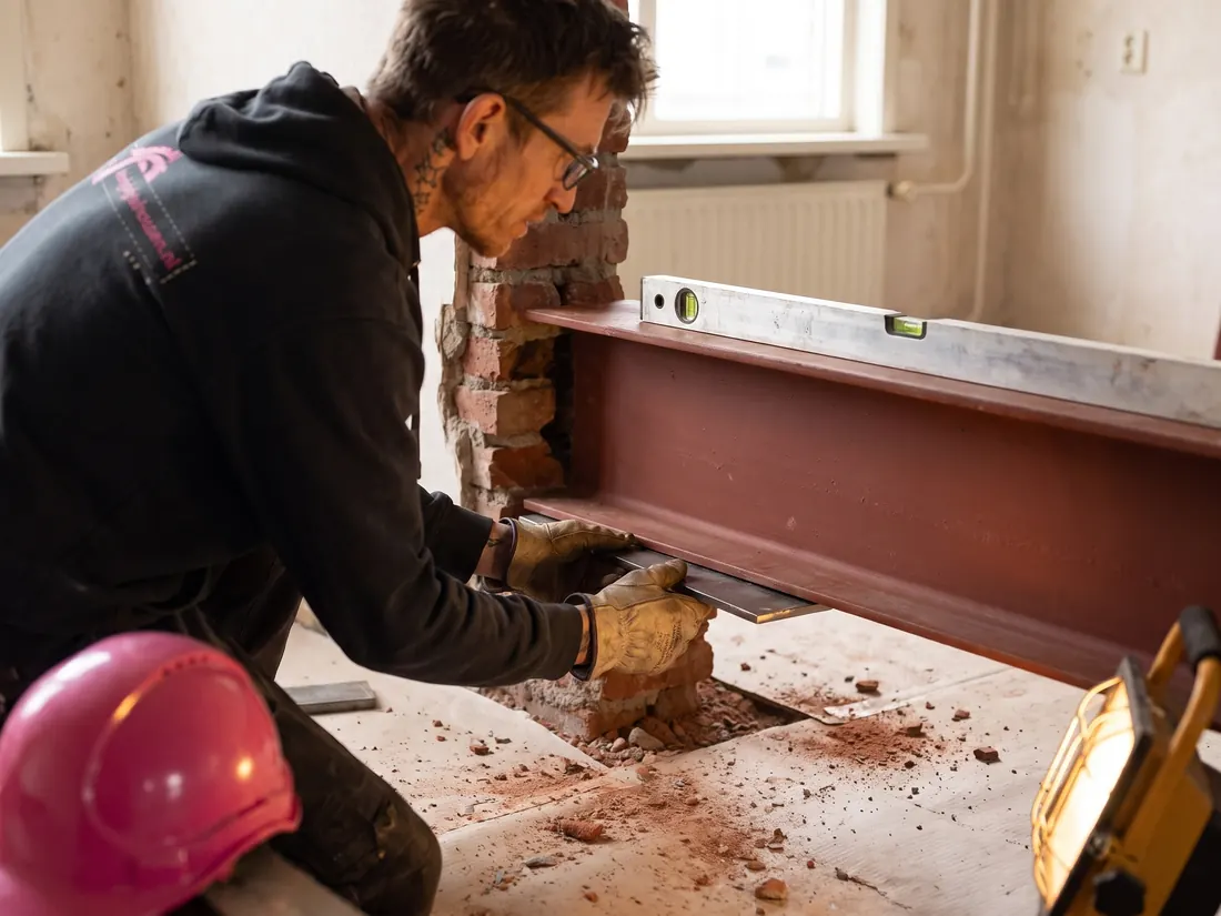 Stalen draagbalk rust op de oplegging in het metselwerk, met waterpas erop