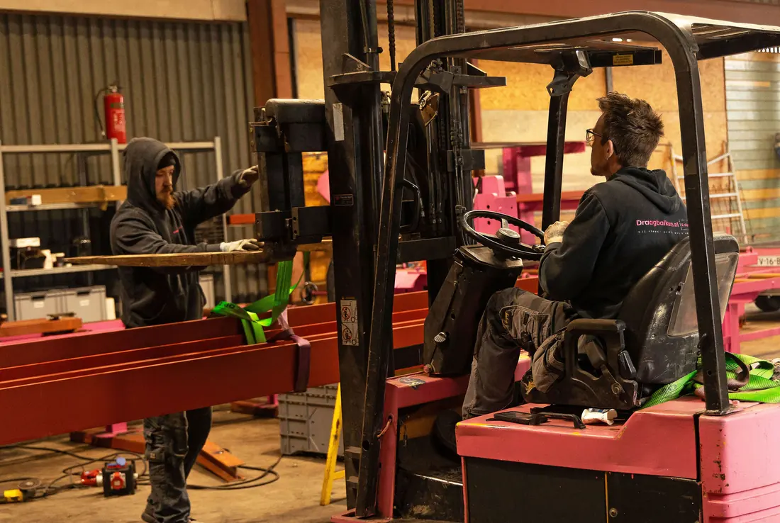 Roze heftruck verplaatst stalen balken in de loods van Draagbalken.nl in Nibbixwoud